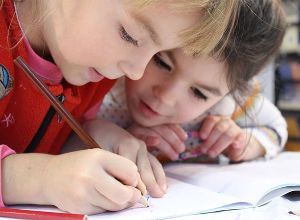 children writing on paper with a pencil