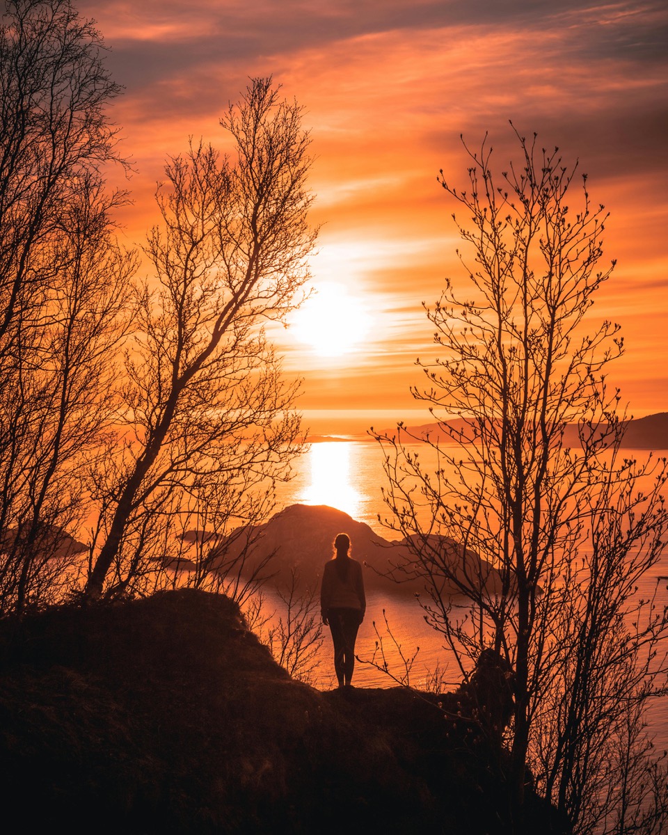 man walking in the sunset overseeing water