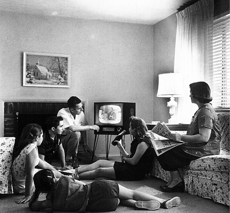 Family sitting together watching television in the 50s settings
